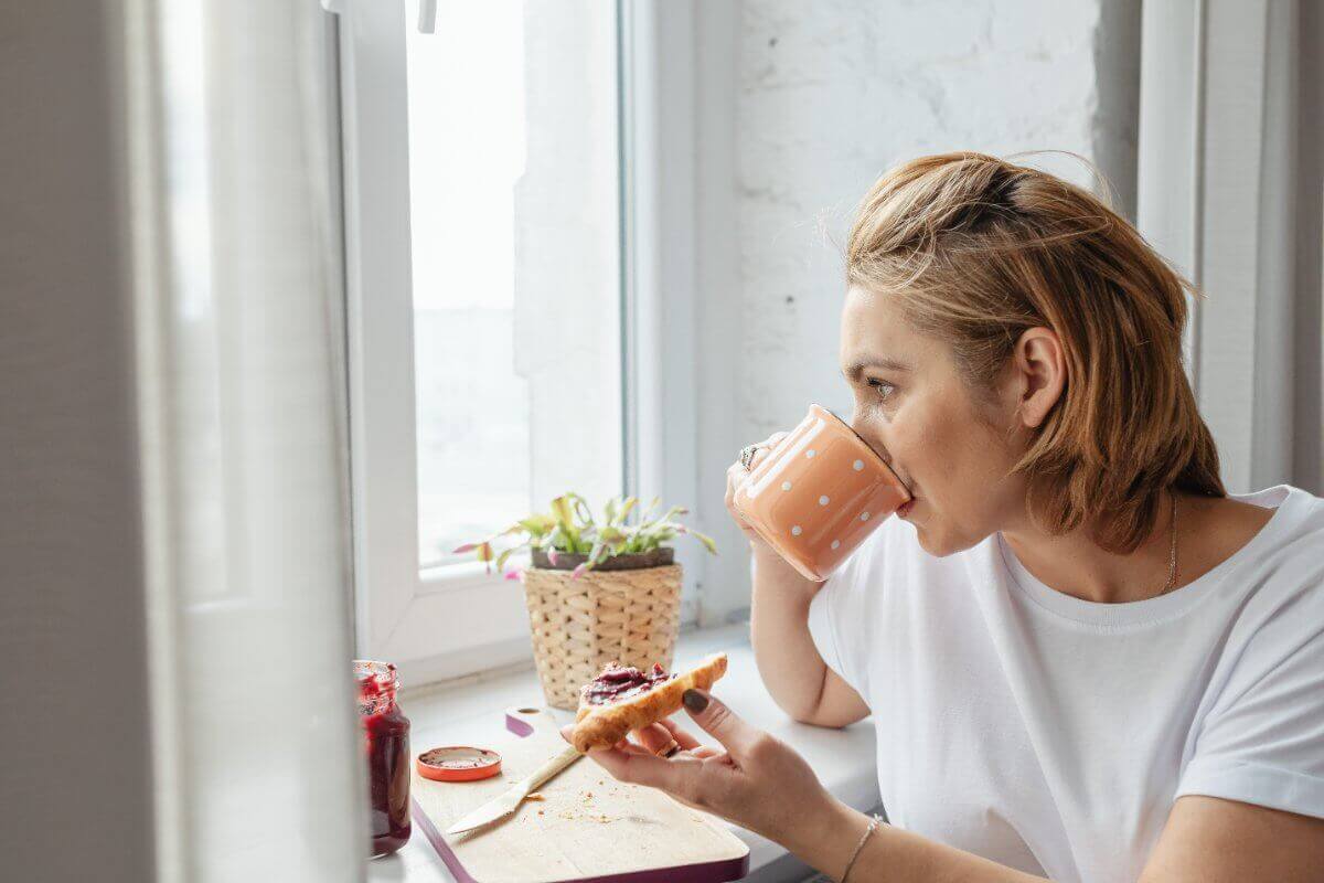 Woman Eating Breakfast Watching Out Of The Window