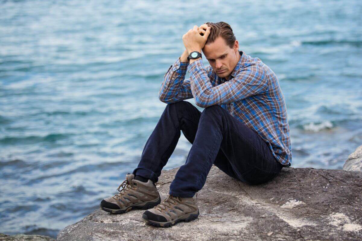 Stressed Man Sitting On A Rock By The Sea