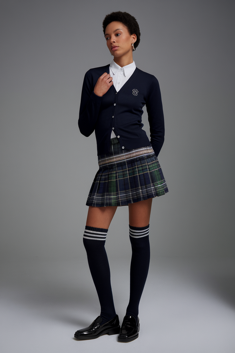 A woman in a plaid pleated skirt, a navy cardigan, and knee-high socks reflects a 90s preppy style.